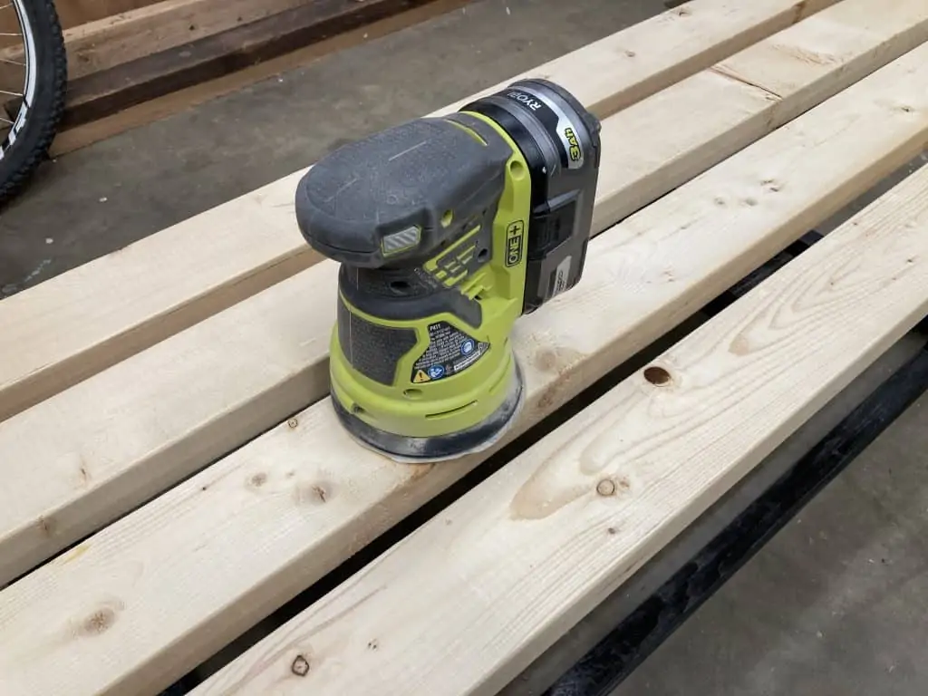 Battery powered orbital sander on 2x4 wood.