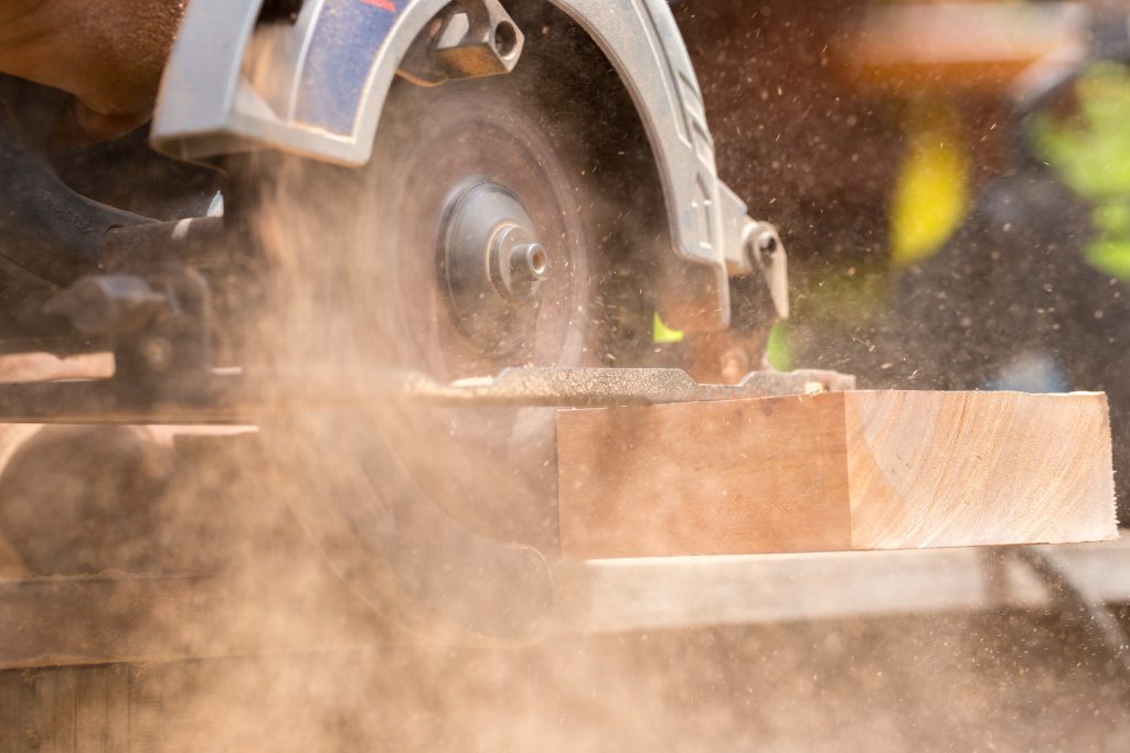 What is a circular saw used for? Image of a circular saw cutting a board with sawdust.